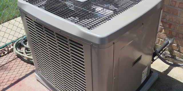 The outdoor unit of a central air conditioner beside a house