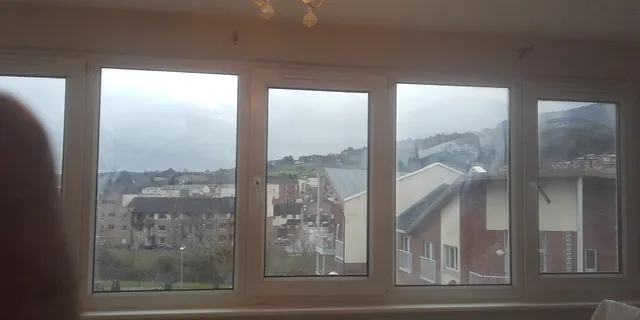 A row of new white replacement windows looking out over a town